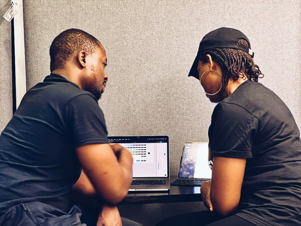 Two Black adults working together on a laptop and tablet